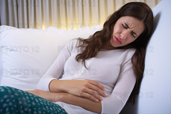 Woman on couch with menstrual cramps clutching stomach in pain. KI generiert, generiert AI generated