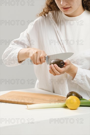 Unrecognizable woman cutting fresh avocado into halves. Concept of balanced eating