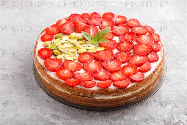 Homemade cake with yoghurt cream, strawberry and pistachio on a gray concrete background. side view, close up
