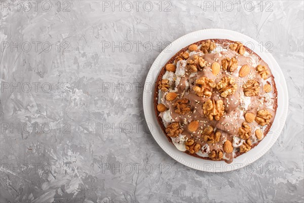 Homemade cake with milk cream, cocoa, almond, hazelnut on a gray concrete background with orange textile. Top view, flat lay, copy space