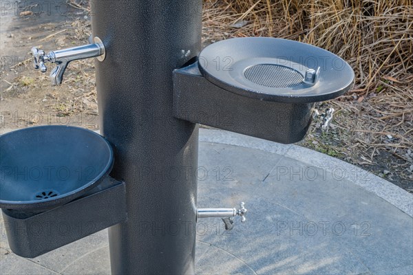 Black metal water drinking fountains near walkway in a public park in South Korea