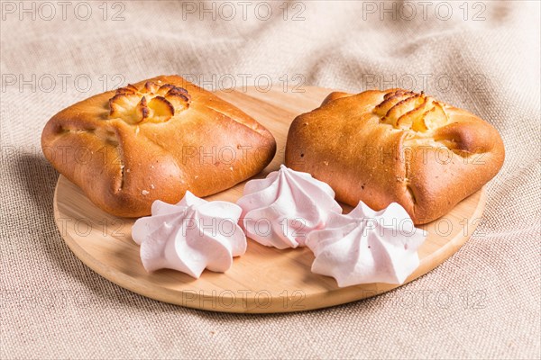 Sweet buns and meringues on a wooden board and linen tablecloth