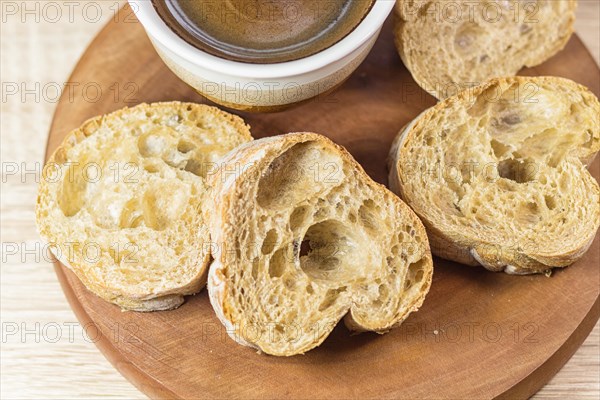 Sliced bread and a cup of coffee on a wooden board and linen tablecloth