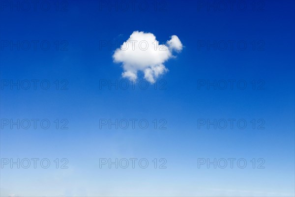 One single small fluffy white fair weather cloud in blue sky