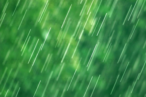 Many bright raindrops of a rain shower against green background, motion blur