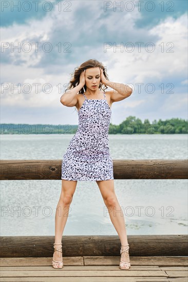 Attractive model in sundress with abstract pattern posing on wooden pier