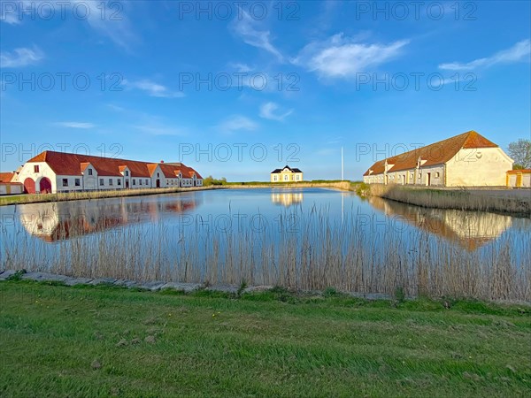 Large houses and the teahouse at Valdemars Slot are reflected in the calm water, Valdemars Slot, Manor Route, Tasinge, Denmark, Europe