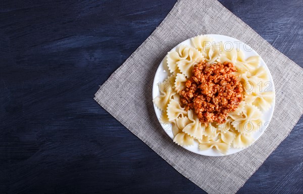 Farfalle bolognese pasta with minced meat on black wooden background. top view, copy space