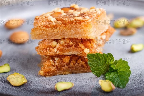 Traditional arabic sweets in gray ceramic plate on a gray concrete background. side view, close up, selective focus