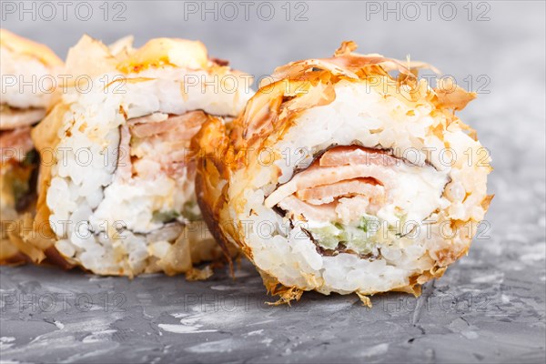 Japanese maki sushi rolls with tuna, cucumber, cheese on black concrete background. Side view, close up, macro