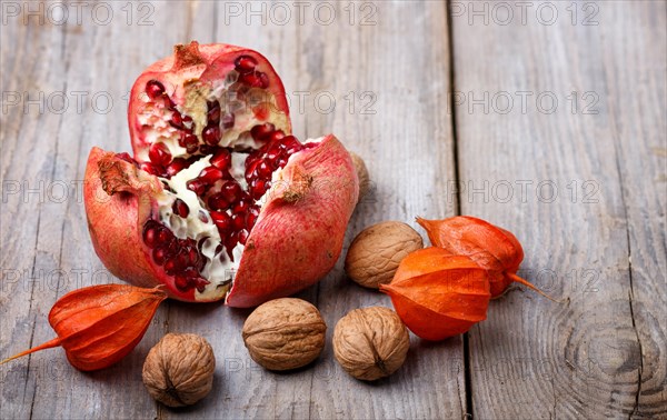 Ripe garnet with walnuts on a rustic wooden background