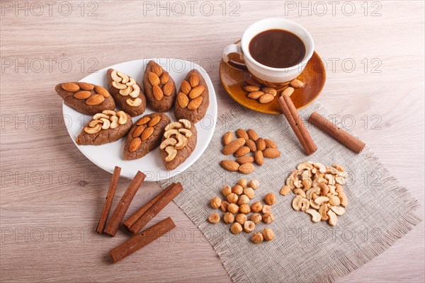 Small cakes potatoes with almonds and cashew nuts on a dessert plate. A cup of coffee, cinnamon, almonds, hazelnuts, cashew on a linen napkin. Still life. Copy space