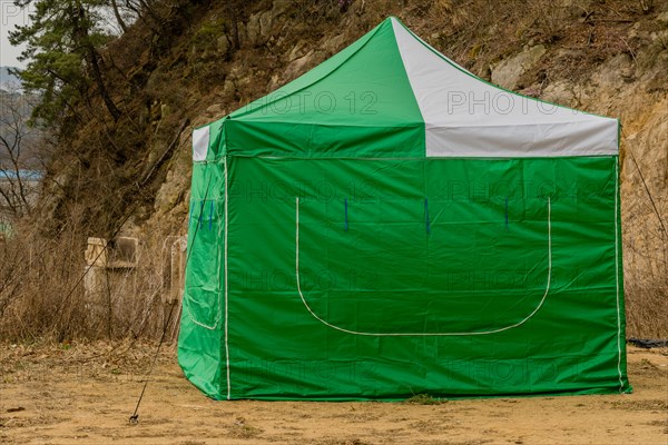 Closeup of green and white canvas tent on bare ground in South Korea