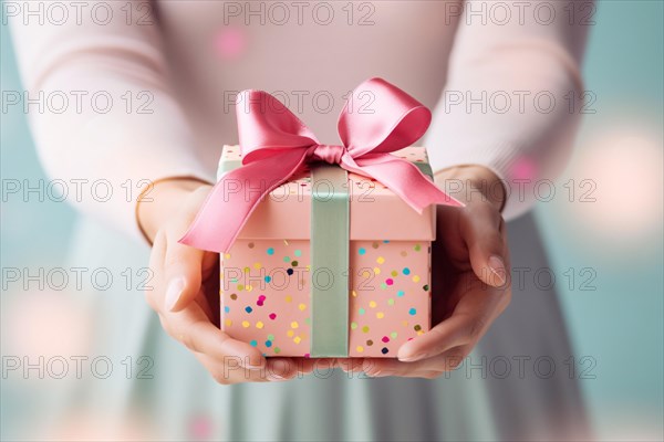 Gift giving. Female hands holding pastel colored gift box with pink bow. KI generiert, generiert AI generated