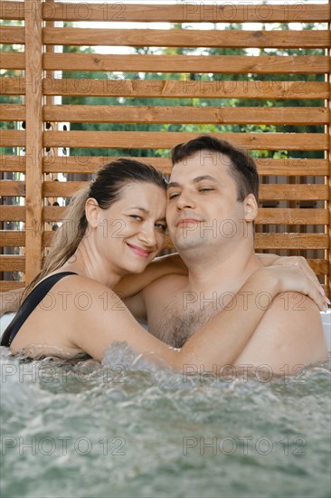 Satisfied woman hugging her husband while relaxing in outdoor spa
