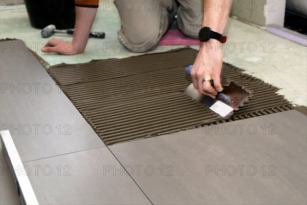 Tiler lays modern large floor tiles in a bathroom