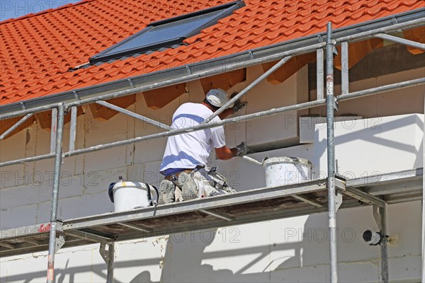 Construction workers insulate a house facade