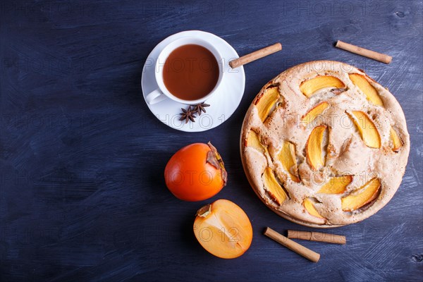 Sweet persimmon pie with cup of cocoa on black wooden background. top view, copy space