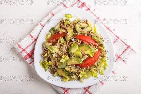 Vegetarian salad of celery, germinated rye, tomatoes and avocado on linen tablecloth, top view
