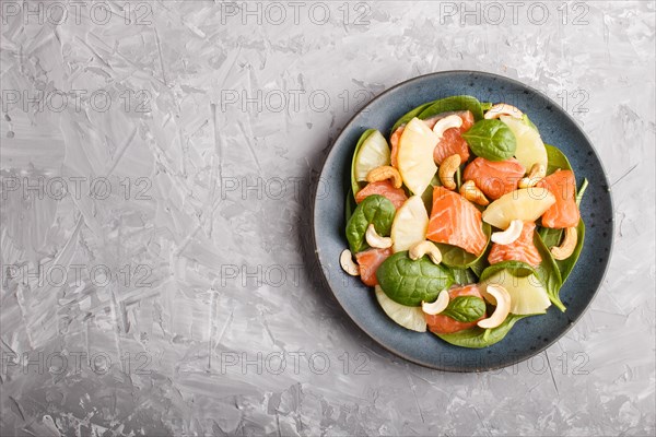Fresh salmon with pineapple, spinach and cashew on a gray concrete background. Top view, copy space, flat lay