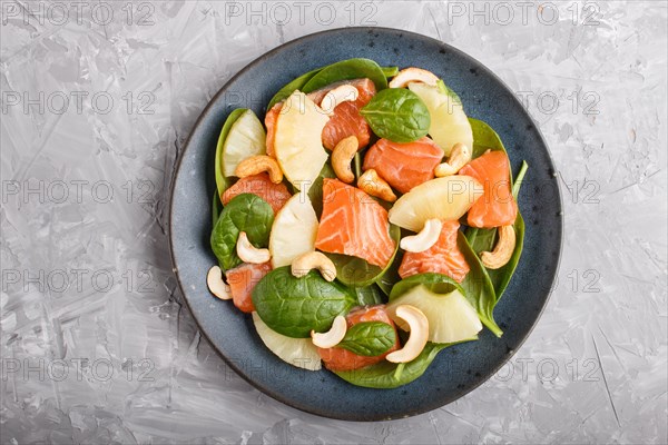 Fresh salmon with pineapple, spinach and cashew on a gray concrete background. Top view, close up, flat lay