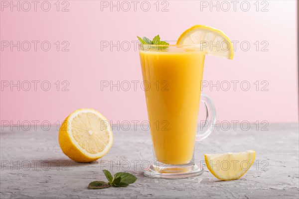 Glass of lemon drink on a gray and pink background. Morninig, spring, healthy drink concept. Side view, close up