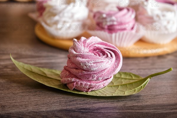 Pink and white homemade marshmallows (zephyr) on a round wooden board on a gray wooden background