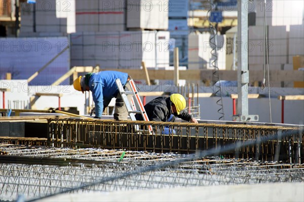 Construction work on the foundations of a large apartment building. The construction workers are wearing construction helmets in accordance with regulations