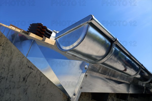 Close-up of a newly installed gutter in the course of tinsmith work on the roof covering