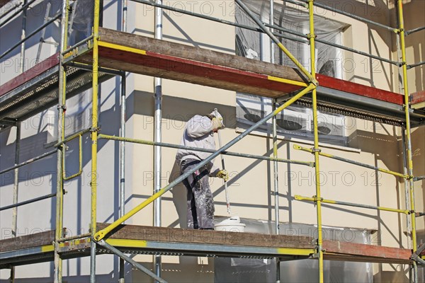 Painter painting the facade of a new residential building (Mutterstadt development area, Rhineland-Palatinate)
