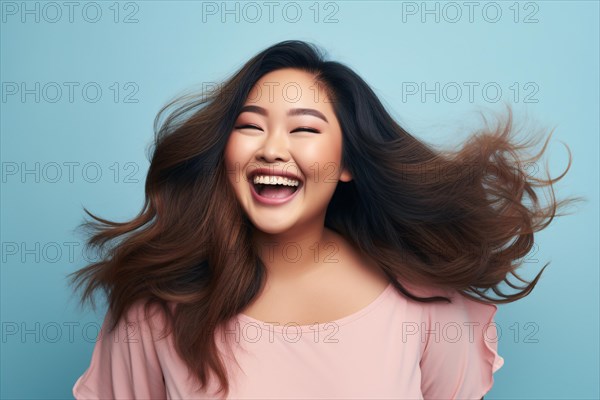 Lauging happy plus size curvy Asian woman in front of blue studio background. KI generiert, generiert AI generated