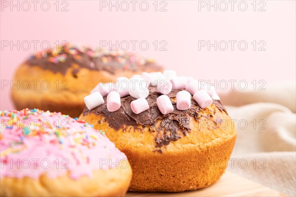 Homemade glazed and decorated easter pies with chocolate eggs and rabbits on a gray and pink background and linen textile. Side view, selective focus, close up