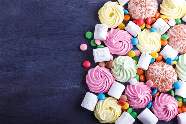 Mixed multicolored candies on black wooden background. copy space, top view, flat lay