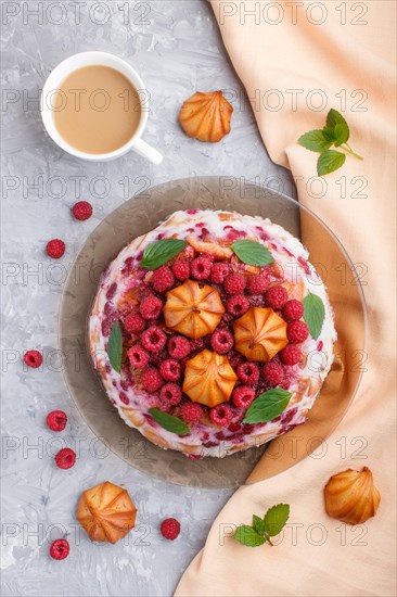 Homemade jelly cake with milk, cookies and raspberry on a gray concrete background with cup of coffee and orange textile. top view. flat lay