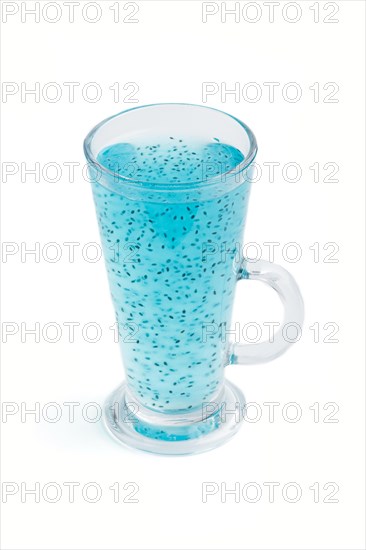 Glass of blueberry blue colored drink with basil seeds isolated on white background. Morninig, spring, healthy drink concept. Side view, close up