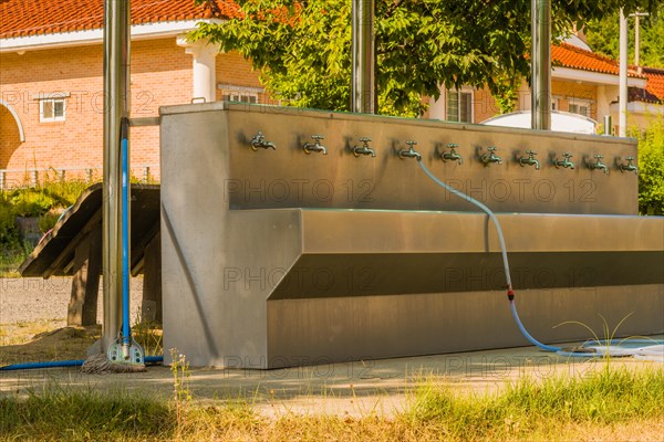 Multifaceted public washing sink and water fountain with hose attached to faucet at edge of public park in rural community in South Korea