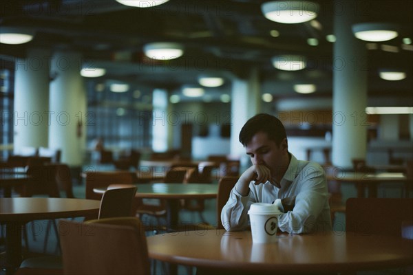 Tired man having coffee in office building cafeteria, AI generated