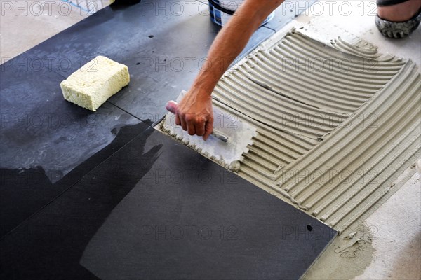 Tiler lays modern large floor tiles in a bathroom