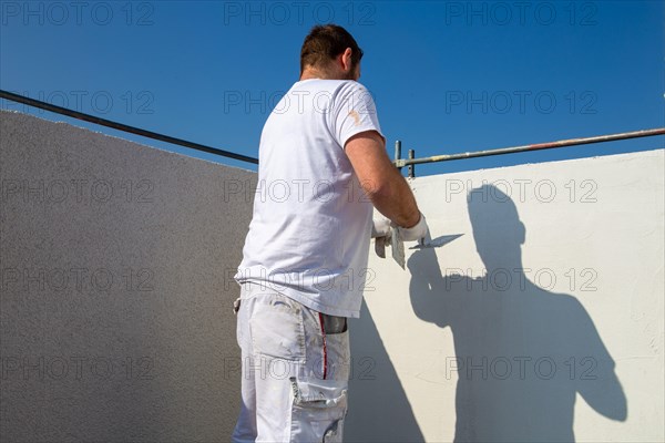 Plasterer plasters the facade of a new building