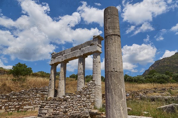 Remains of an ancient temple with columns against a cloudy blue sky, Archaeological site, Ancient Messene, capital of Messinia, Messini, Peloponnese, Greece, Europe