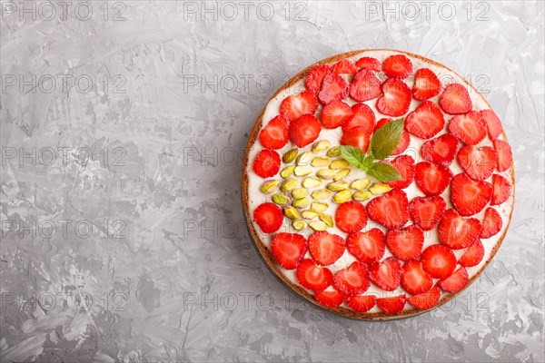 Homemade cake with yoghurt cream, strawberry and pistachio on a gray concrete background. top view. flat lay, copy space
