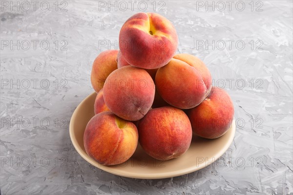 Fresh peaches on a plate on gray concrete background. side view, close up