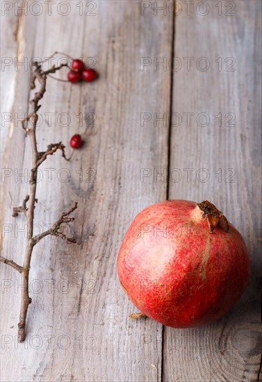 Ripe garnet with a branch on a rustic wooden background