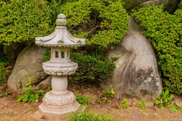 Concrete spirit house in front of boulders and green bushes in public park in South Korea