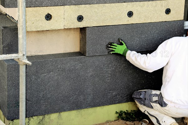 Construction workers insulate a house facade