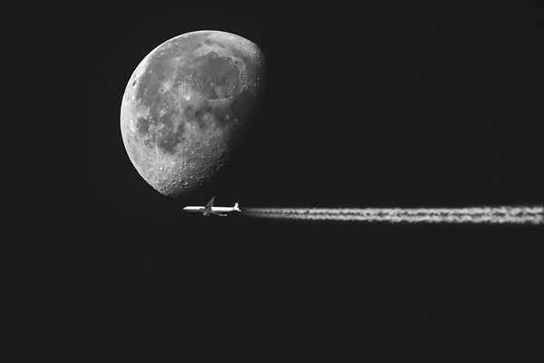 Aeroplane with contrails in front of a waning moon in the early morning sky, Bavaria, Germany, no montage, Europe