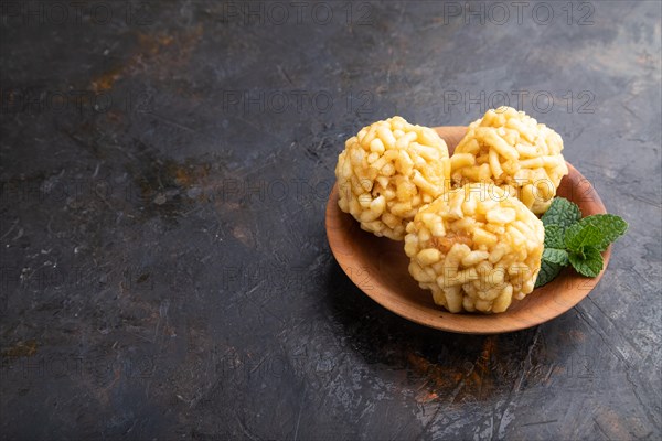 Traditional Tatar candy chak-chak made of dough and honey in wooden plate on a black concrete background. Side view, copy space