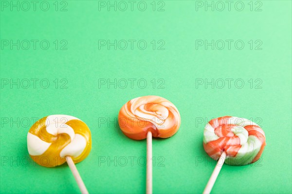 Three lollipop candies on green pastel background. copy space, top view, flat lay