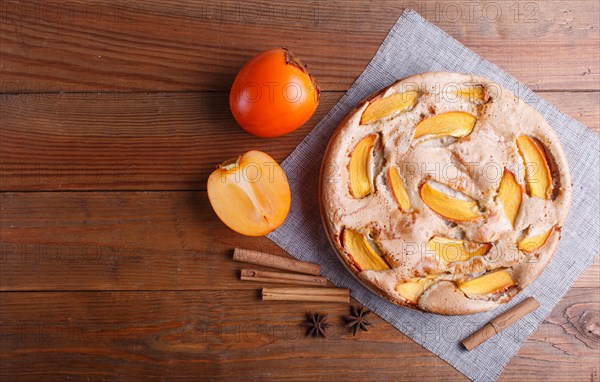 Sweet persimmon pie on brown wooden background. top view, copy space