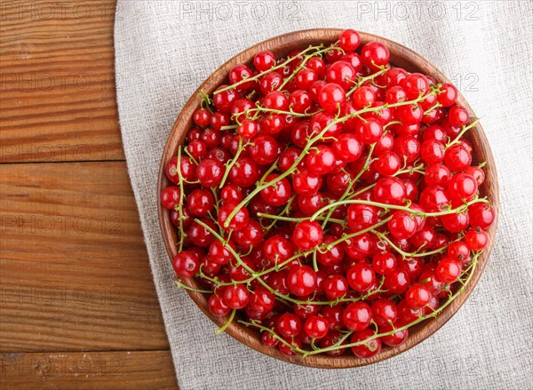 Fresh red currant in wooden bowl on wooden background. top view, flat lay, close up